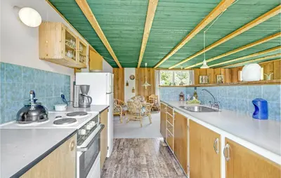 a kitchen with wooden cabinets and a green ceiling at Holiday Home Sølvmågevej Hurup Thy Ii in Sindrup
