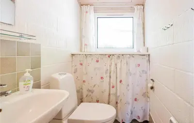 a bathroom with a toilet and a sink and a window at Holiday Home Limfjordsvangen Snedsted Vi in Snedsted