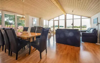 a dining room with a wooden table and black chairs at Holiday Home Limfjordsvangen Snedsted Vi in Snedsted