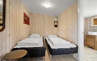 two beds in a room with a wooden wall at Holiday Home Pinen Roslev X in Roslev