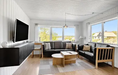 a living room with a black couch and a tv at Holiday Home Pinen Roslev X in Roslev
