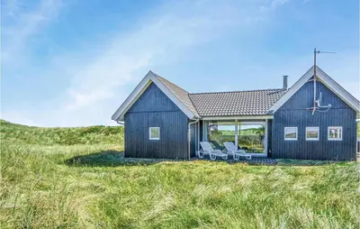 a blue house on a hill with two chairs at Nice Home In Thisted With Kitchen in Thisted