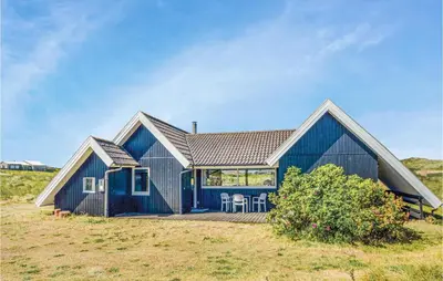 a blue house with a porch and chairs on a field at Nice Home In Thisted With Kitchen in Thisted