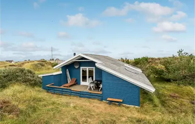 a blue house with a deck on a beach at Holiday Home Svenstibakkevej Ii in Frøstrup