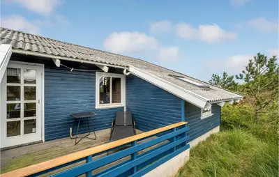 a blue house with a bench on a deck at Holiday Home Svenstibakkevej Ii in Frøstrup