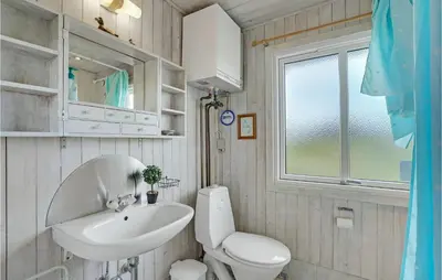 a bathroom with a sink and a toilet and a window at Holiday Home Svenstibakkevej Ii in Frøstrup