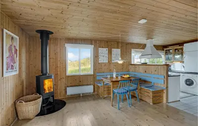 a kitchen with a wood stove and a table and chairs at Holiday Home Svenstibakkevej Ii in Frøstrup
