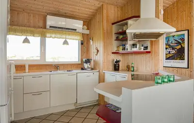 a kitchen with wooden walls and white cabinets and a sink at Holiday Home Svenstibakkevej I in Frøstrup