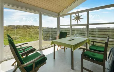 a dining room with a table and chairs and windows at Holiday Home Svenstibakkevej I in Frøstrup