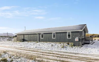 a gray building with snow on the ground next to train tracks at Gorgeous Home In Thisted With Sauna in Thisted