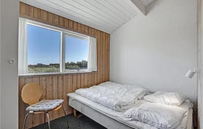 a bed sitting in a room with a window at Stunning Home In Thisted With Sauna in Klitmøller