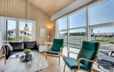 a living room with a table and chairs and windows at Stunning Home In Thisted With Sauna in Klitmøller