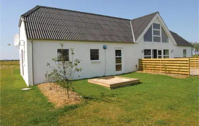 a white house with a wooden fence in a yard at Holiday Home Glombak in Vesløs