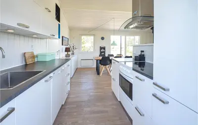 a kitchen with white cabinets and a wooden floor at Holiday Home Johnsvej Thisted V in Thisted