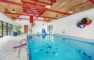 an indoor swimming pool with blue tile floors and wood ceilings at Rishøj in Løgstrup