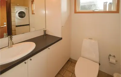 a bathroom with a sink and a toilet and a washing machine at Holiday Home Fjordparken Farsø Iv in Farsø