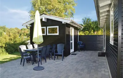 a patio with a table and chairs and an umbrella at Holiday Home Fjordparken Farsø Iv in Farsø