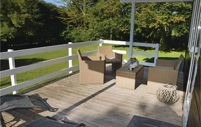 a deck with chairs and a table and a fence at Holiday Home Fjordparken Farsø Iv in Farsø