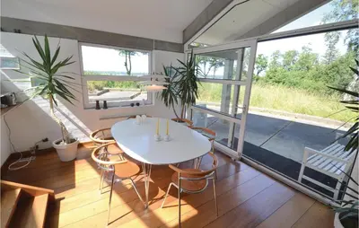 a room with a white table and chairs and windows at Holiday Home Hesselvej in Farsø