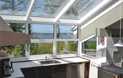 a kitchen with large windows and a sink and a counter at Holiday Home Hesselvej in Farsø