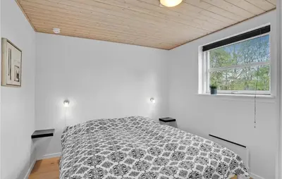 a white bedroom with a bed and a window at Holiday Home Marthasvej in Løgstør