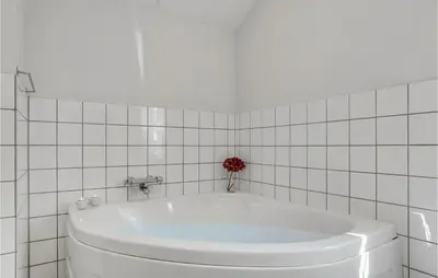 a white tub in a white tiled bathroom at Holiday Home Furvej in Vesløs