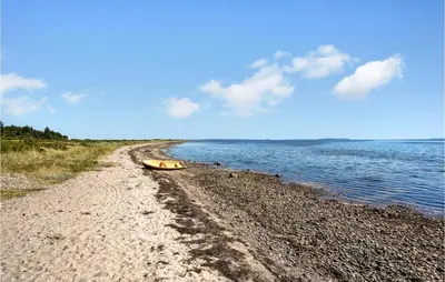 a beach with a boat sitting on the shore at Holiday Home Furvej in Vesløs