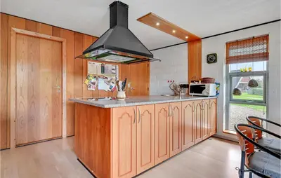 a kitchen with wooden cabinets and a stove at Holiday Home Eskovvej in Roslev