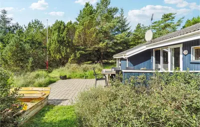a blue house with a patio in the yard at Holiday Home Revlingestien Fjerritslev V in Fjerritslev