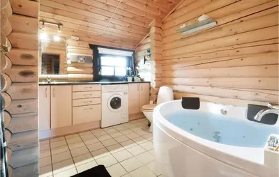 a bathroom with a tub and a wooden wall at Holiday Home Lyngbjergvej Vi in Fjerritslev