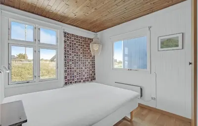 a bedroom with a bed and two windows at Holiday Home Svenstibakkevej Denm in Frøstrup