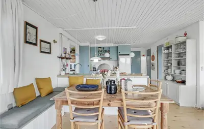 a kitchen and dining room with a wooden table and chairs at Holiday Home Svenstibakkevej Denm in Frøstrup