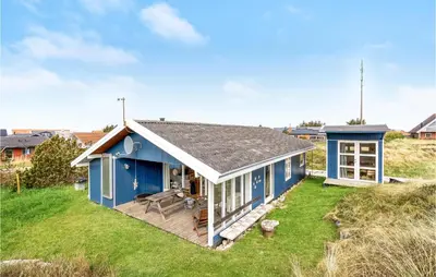 a blue house on a hill with a grass yard at Holiday Home Svenstibakkevej Denm in Frøstrup