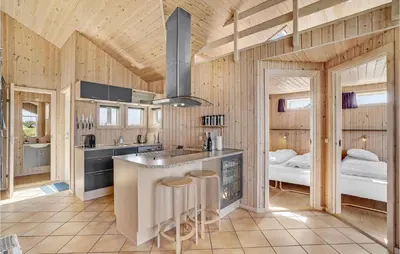 a kitchen with wooden walls and a kitchen island with bar stools at Holiday Home Svenstibakkevej Denmark I in Frøstrup