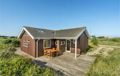 a small wooden house with a table on a deck at Holiday Home Svenstibakkevej Denmark I in Frøstrup