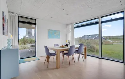 a dining room with a table and chairs and windows at Holiday Home Hjelmevej Ulfborg Vi in Ulfborg