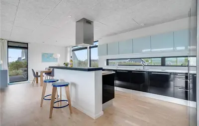 a kitchen with black and white cabinets and a table at Holiday Home Hjelmevej Ulfborg Vi in Ulfborg