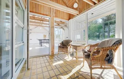 a screened in porch with wicker chairs and a table at Holiday Home Tulipanvej Fjerritslev I in Fjerritslev