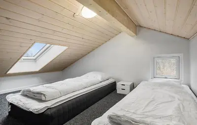 a attic bedroom with two beds and a window at Holiday Home Kronvildtvej Brovst Vi in Brovst