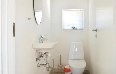 a white bathroom with a sink and a toilet at Holiday Home Kronvildtvej Brovst Vi in Brovst