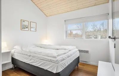 a white bedroom with a bed and a window at Holiday Home Kronvildtvej Brovst Vi in Brovst