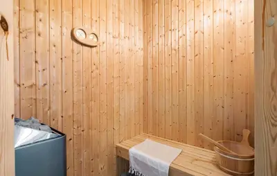a sauna with a wooden wall and a bucket at Holiday Home Kronvildtvej Brovst Vi in Brovst