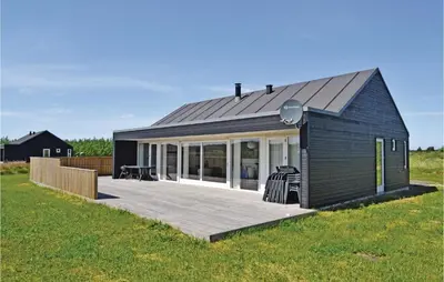 a black house with a deck in a field at Holiday Home Kronvildtvej Brovst X in Brovst