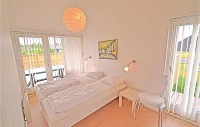 a white bedroom with a bed and a table and chairs at Holiday Home Kronvildtvej Brovst X in Brovst