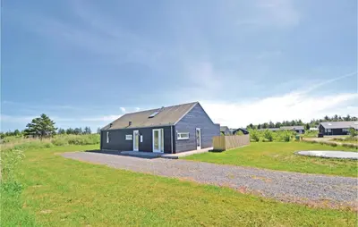 a black house with a gray roof on a grass field at Holiday Home Kronvildtvej Brovst X in Brovst