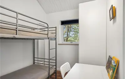 a bedroom with bunk beds and a table and a desk at 4 Bedroom Cozy Home In Brovst in Brovst