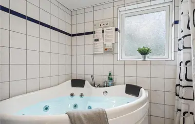 a bath tub in a tiled bathroom with a window at 4 Bedroom Cozy Home In Brovst in Brovst