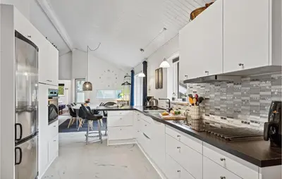 a kitchen with white cabinets and a dining room at 4 Bedroom Cozy Home In Brovst in Brovst