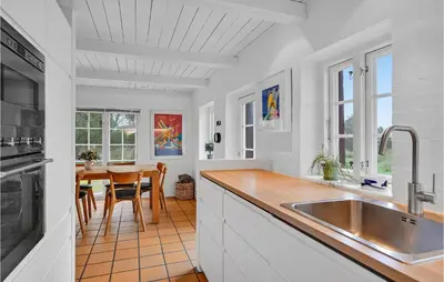 a kitchen with a sink and a table in it at Pee Klims Hus in Brovst