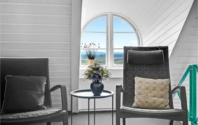 two chairs and a table with a vase of flowers at Pee Klims Hus in Brovst